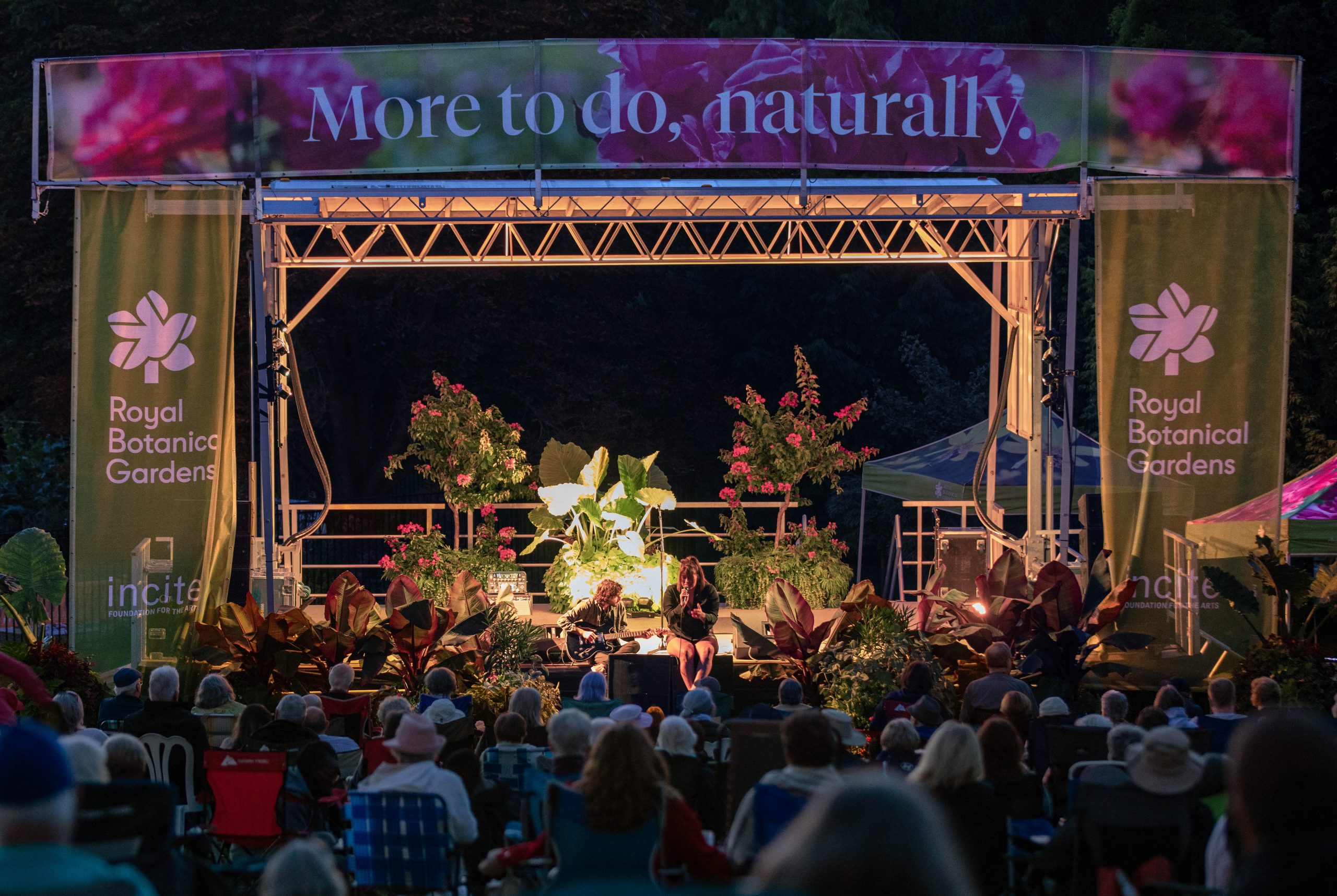 Outdoor concert in the gardens on an open stage decorated with plants